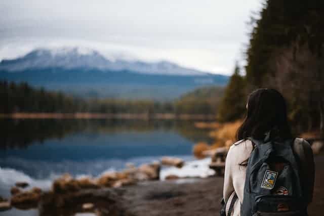 woman staring out at view of mountains and lake how-to-plan-a-solo-trip