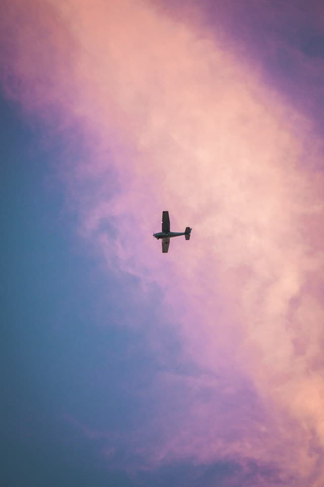 view of a small plane flying over Miami against colorful pink and purple skies