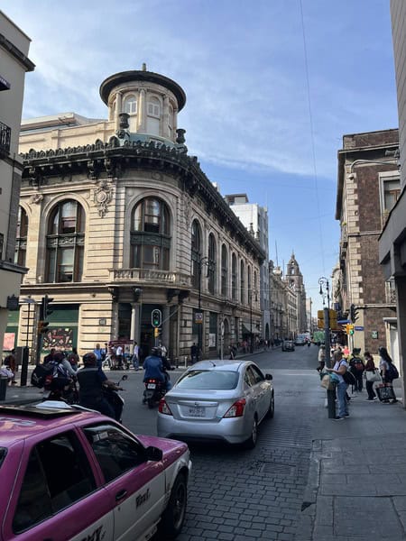 cars on a road, including a pink taxi, in Mexico City center