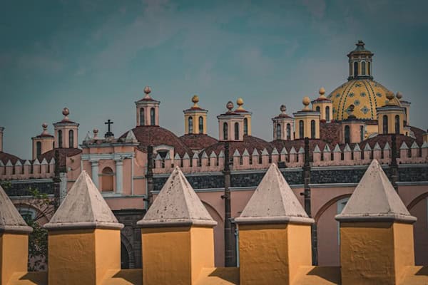 ornate pink and yellow church with turrets in the foreground and dome in background