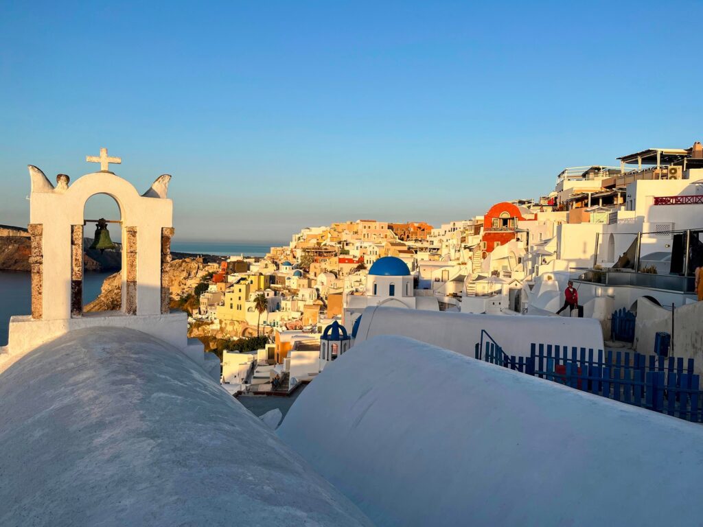 sunrise over whitewashed buildings with blue and red roofs in Oia