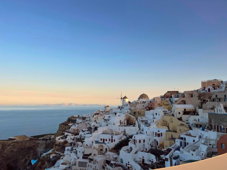 view of cliffside buildings in Oia, Santorini on right and sea on the left
