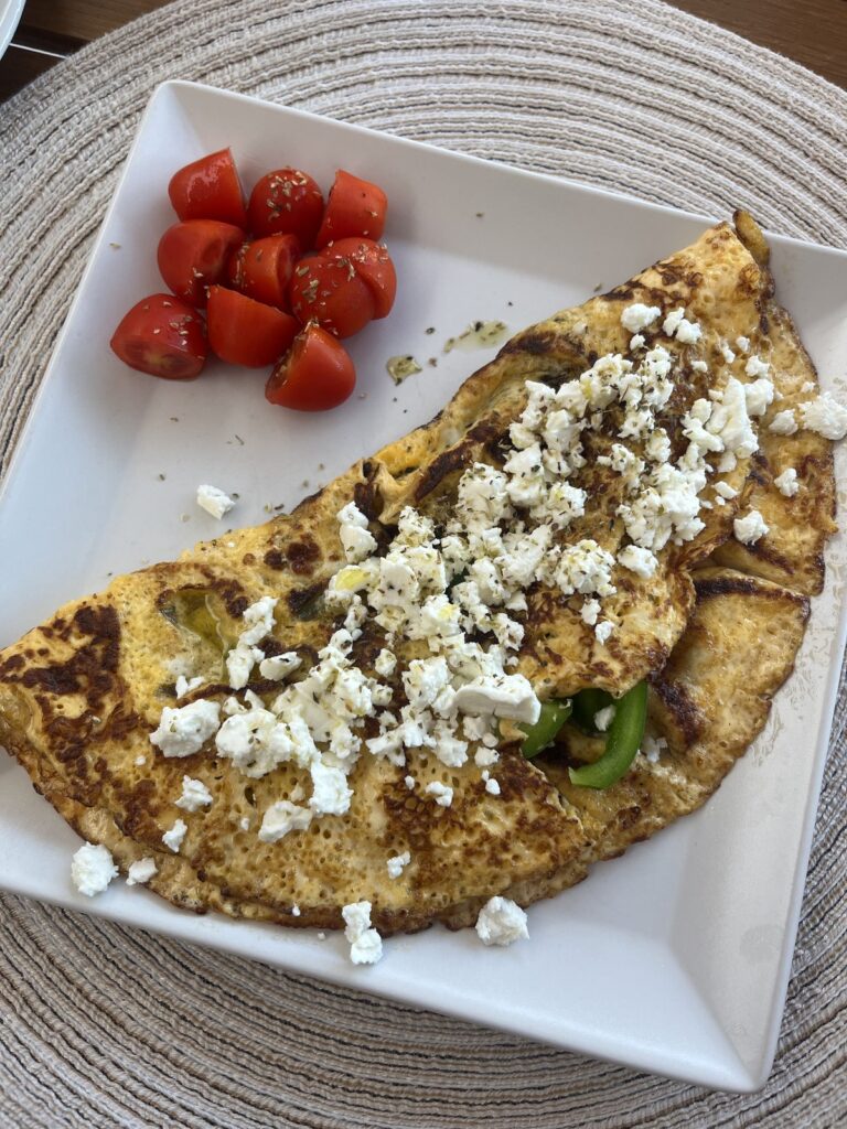 omelet topped with feta cheese and tomatoes on the side of the plate