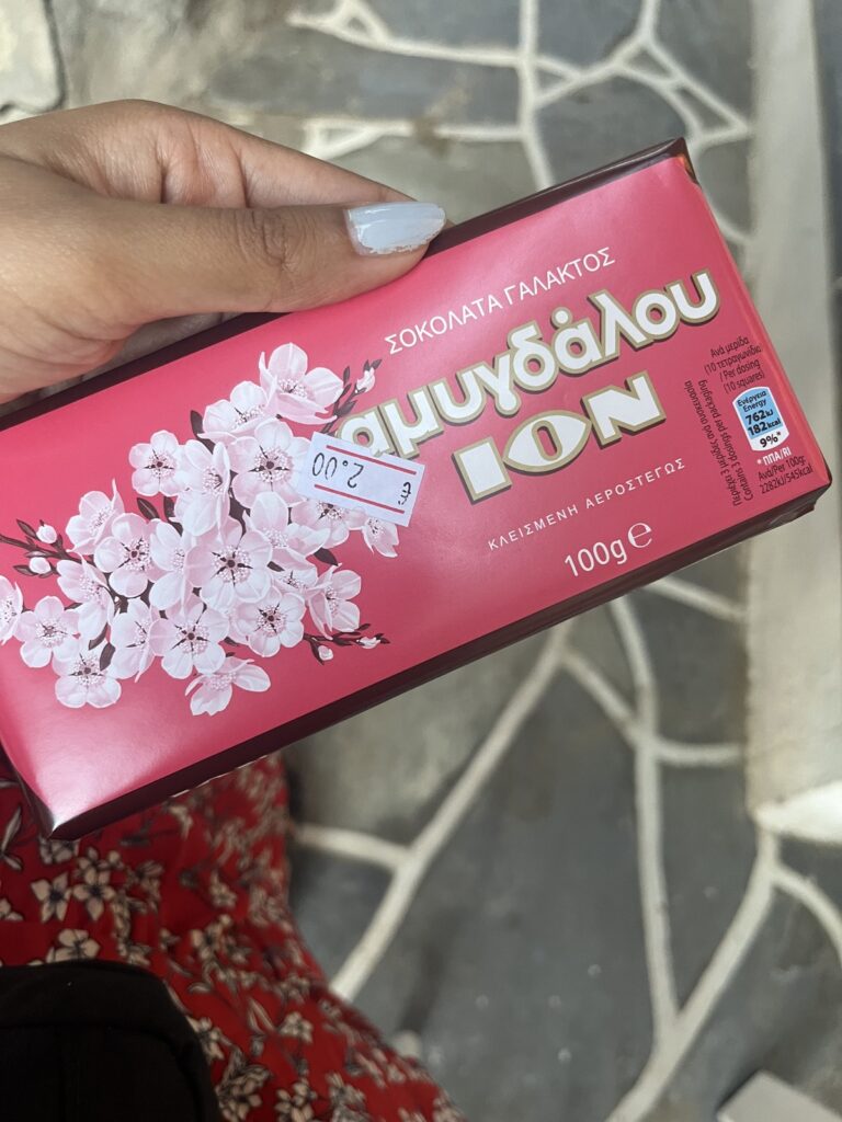hand holding a pink wrapped chocolate bar with printed white and pink flowers on it and the name of the chocolate on it: ION