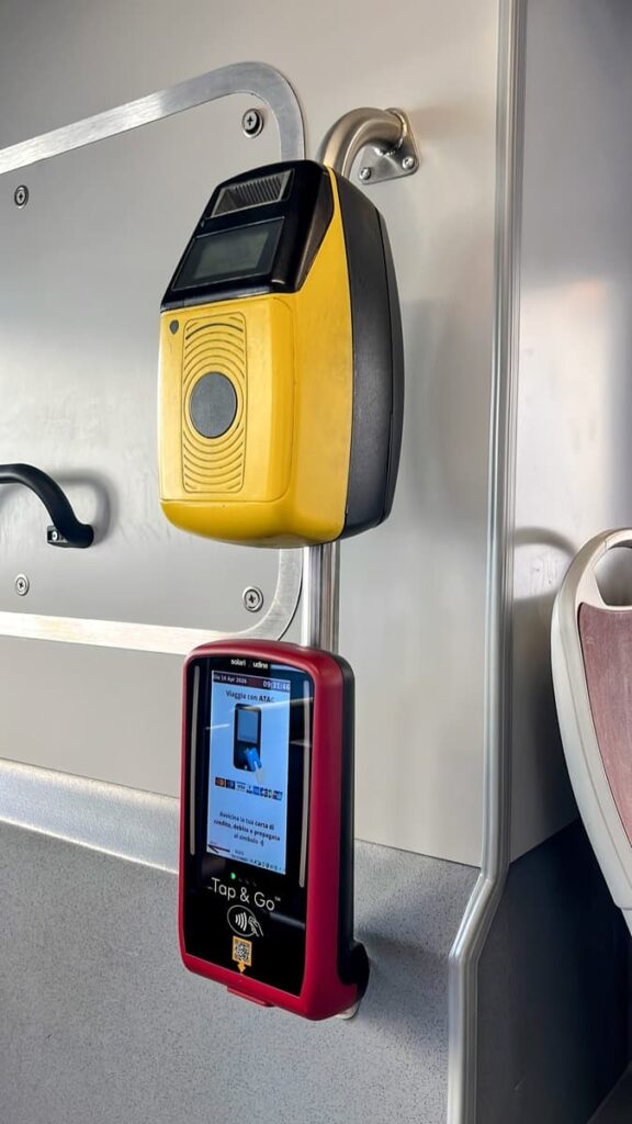 Public transit card validator mounted inside a train or tram in Italy with a “Tap and Go” payment screen visible below the yellow ticket machine. Useful setup for travelers using the best eSIM for Italy while navigating public transportation.